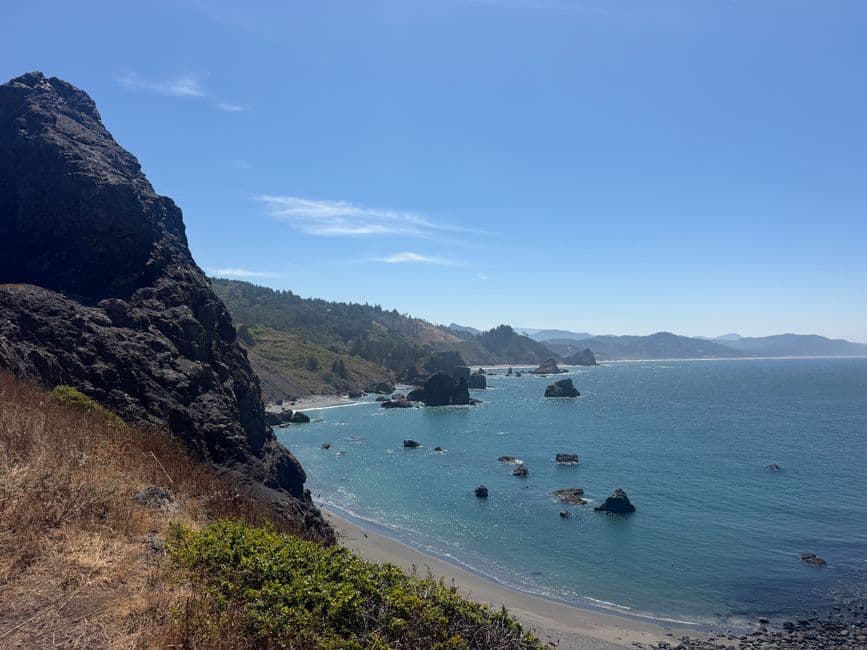 Beautiful view of the Oregon coastline with rocky cliffs and clear blue ocean under a sunny sky.